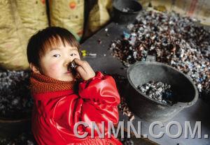 個小朋友在臺州市路橋區(qū)峰江街道一家拆解小作坊內玩分揀出來的金屬。